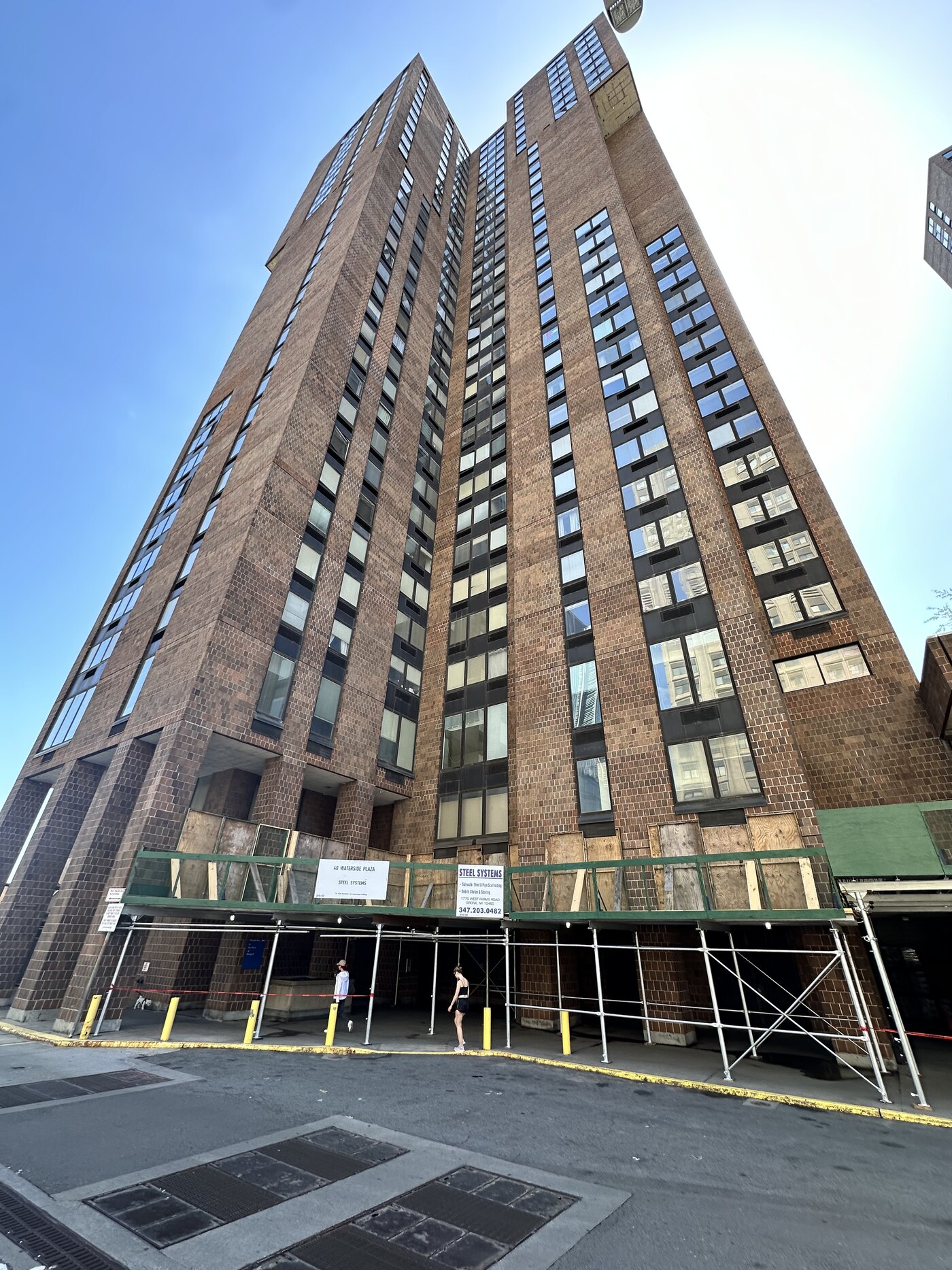 An occupied high-rise under window replacement with sidewalk protection